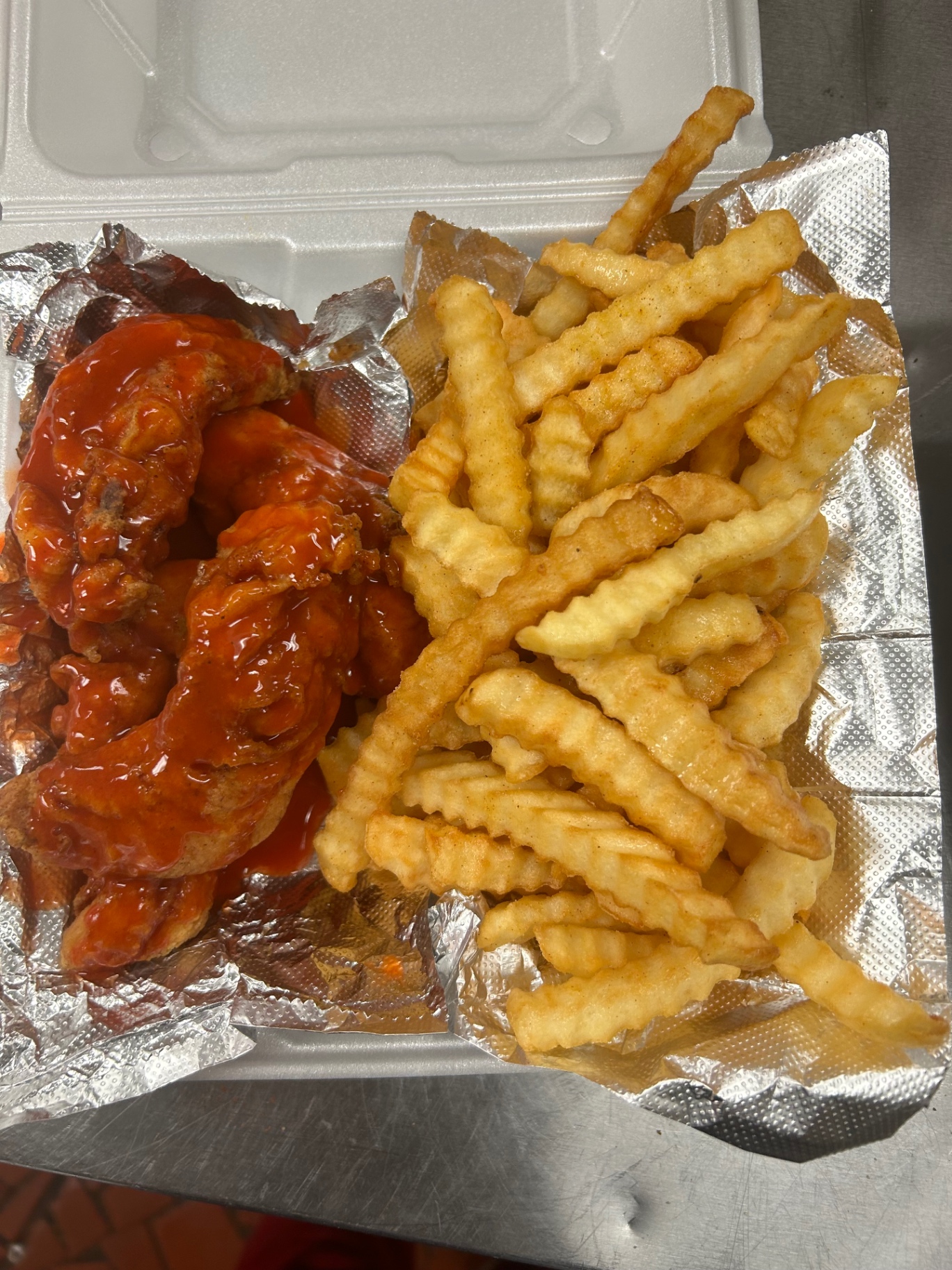 Hot wings tossed in sauce with a side of crinkle fries