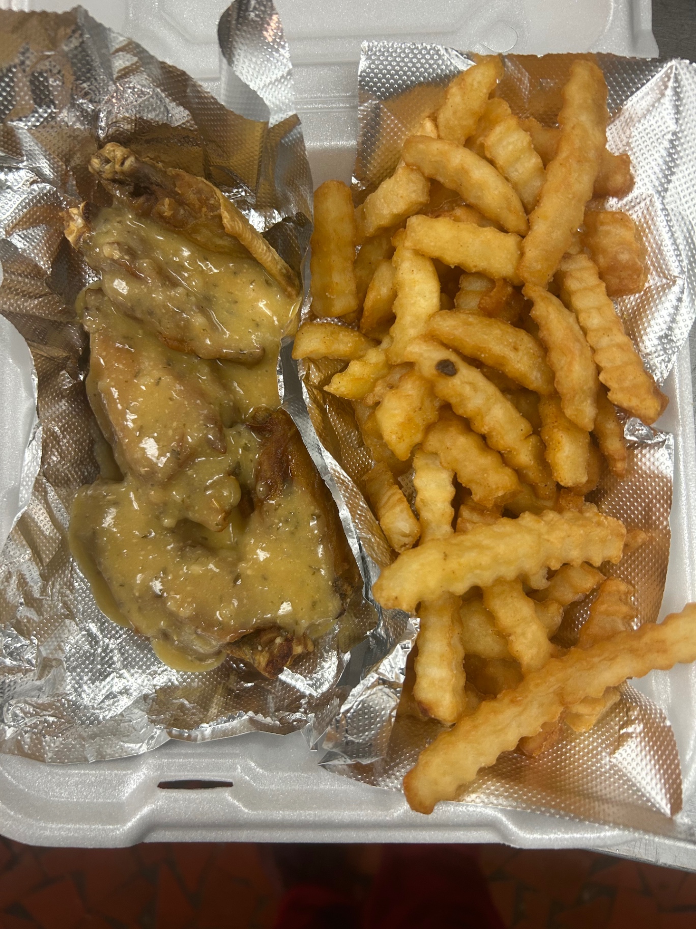 Garlic pepper wings coated in sauce with crinkle fries